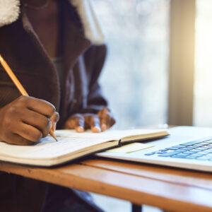 Student, hands and writing in notebook, studying and learning for exams, test and creative. Black p.